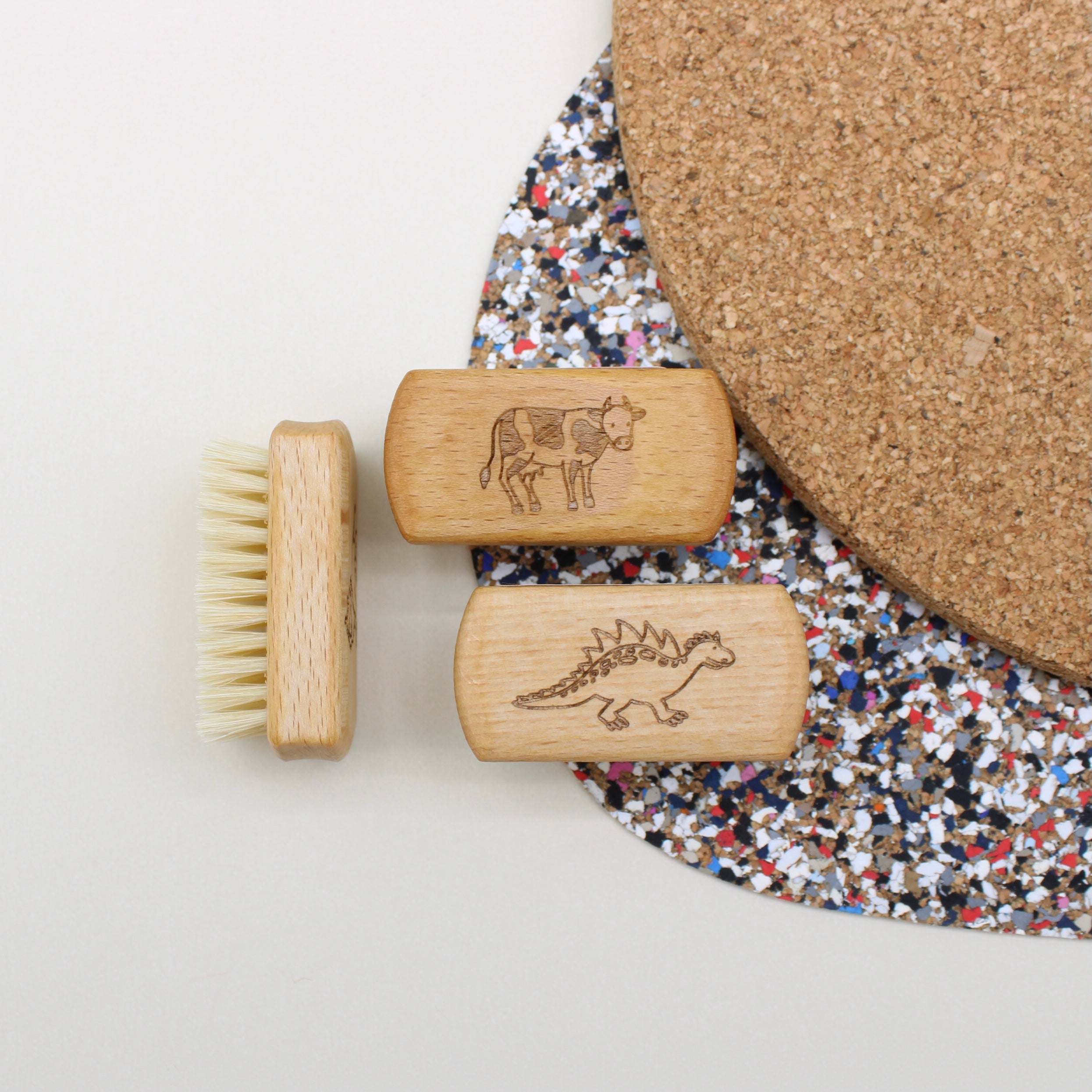Three wooden brushes with engraved designs on a textured surface.